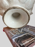 Heirbloom Studio off-white ceramic artichoke pedestal bowl base showing rustic distressed detail on a stack of books