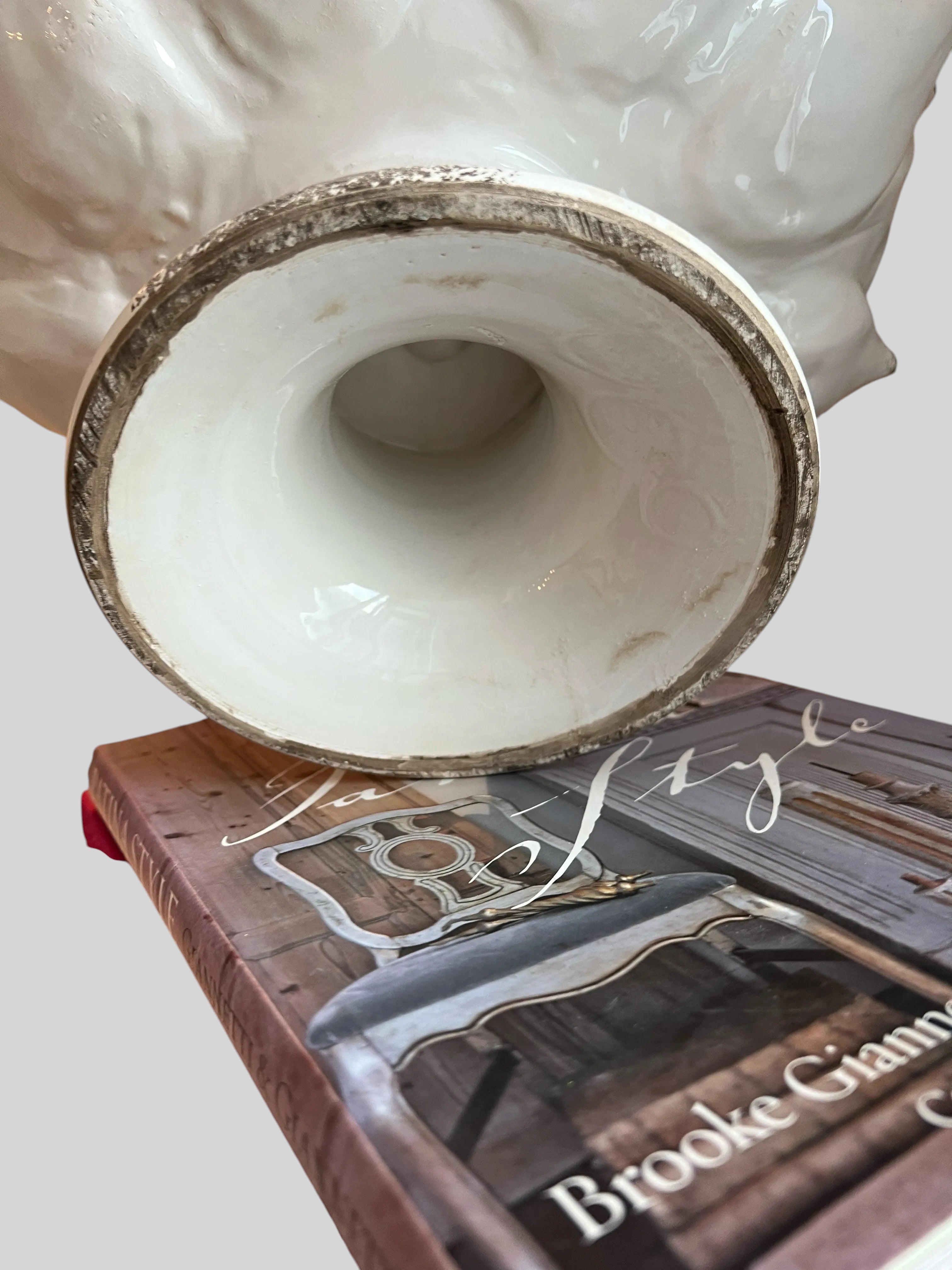 Heirbloom Studio off-white ceramic artichoke pedestal bowl base showing rustic distressed detail on a stack of books