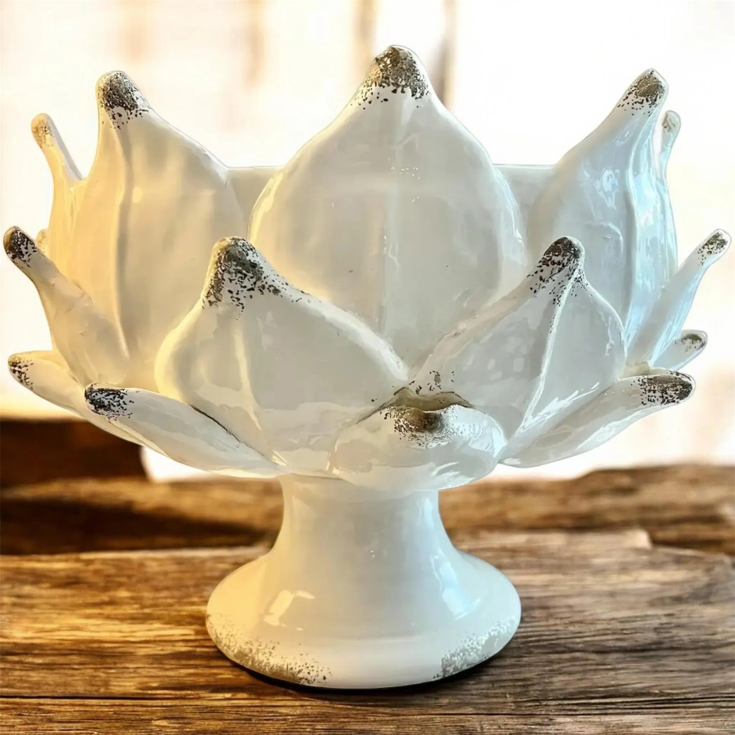 Heirbloom Studio off-white ceramic artichoke pedestal bowl with rustic distressed petal tips on a wooden table.