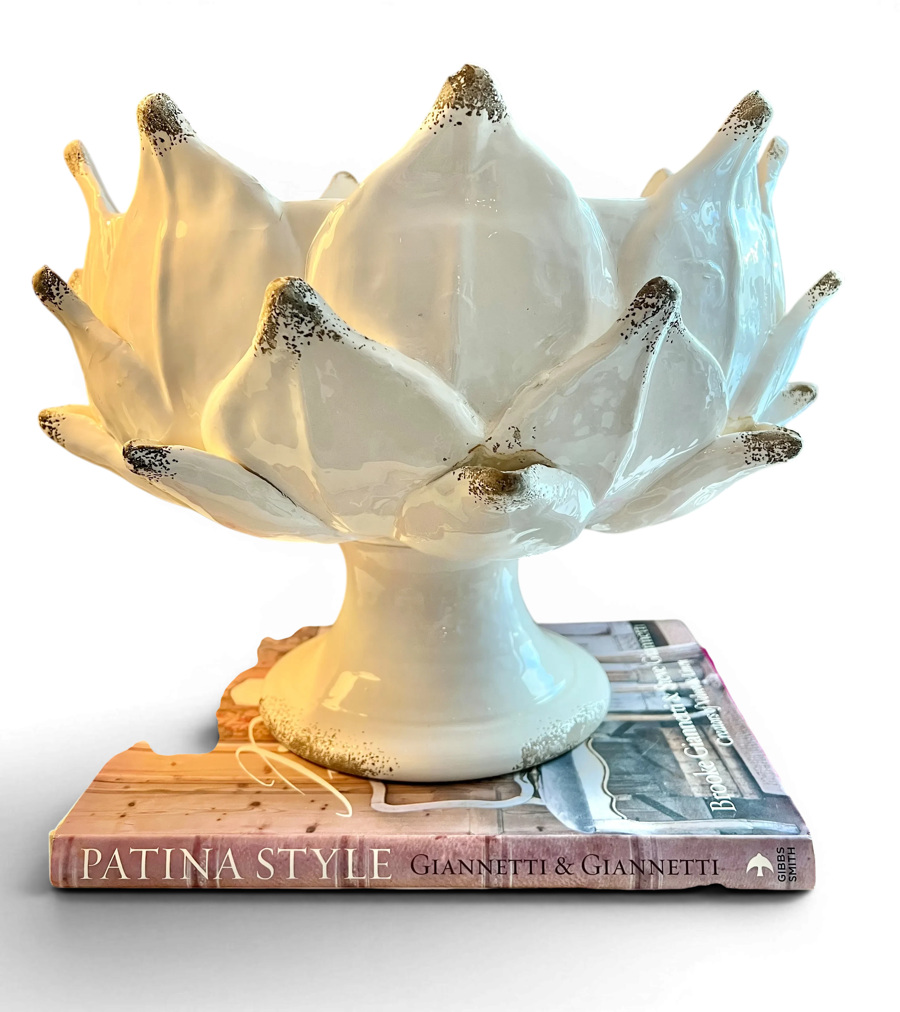 Heirbloom Studio off-white ceramic artichoke pedestal bowl with rustic distressed petal tips on stacked books
