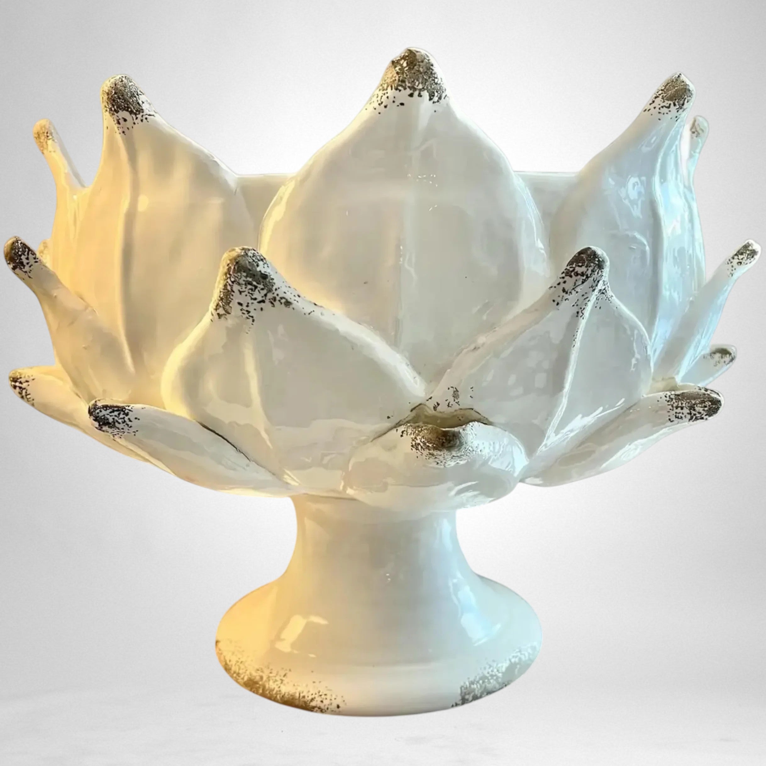 Heirbloom Studio off-white ceramic artichoke pedestal bowl with rustic distressed petal tips on a wooden table.