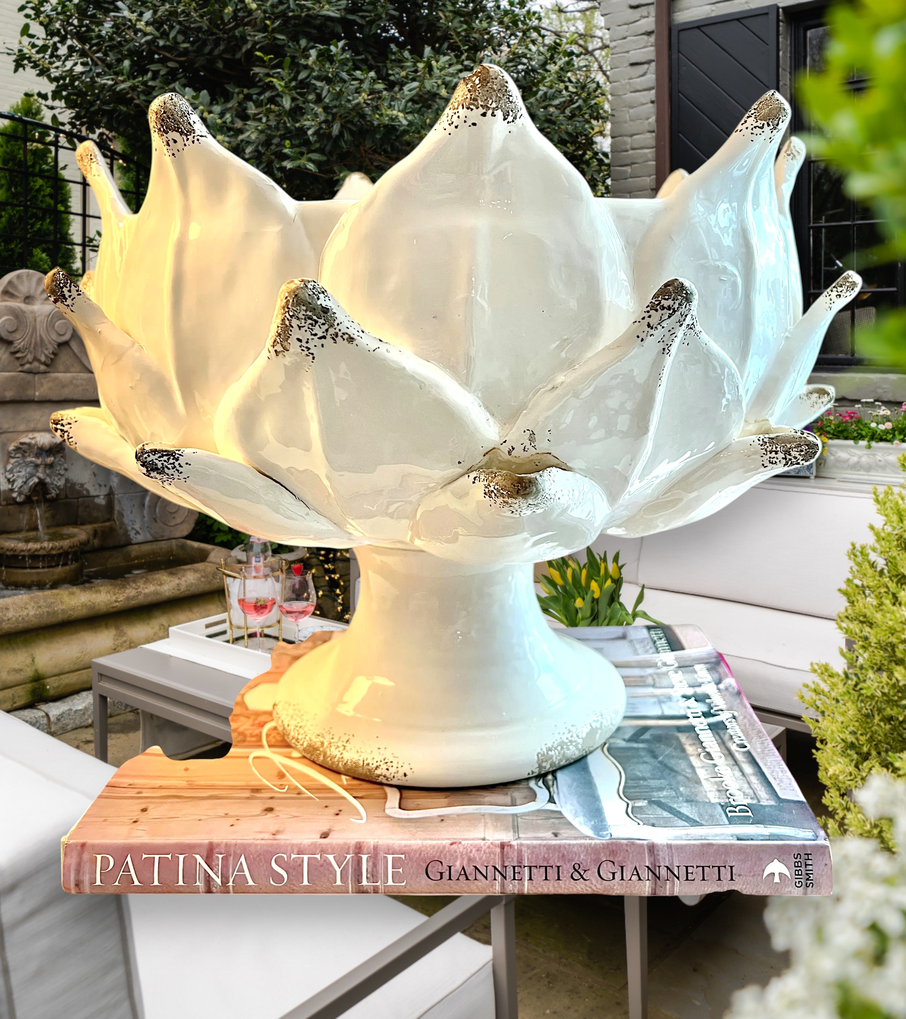 Heirbloom Studio off-white ceramic artichoke pedestal bowl with rustic distressed petal tips on stacked coffee books.